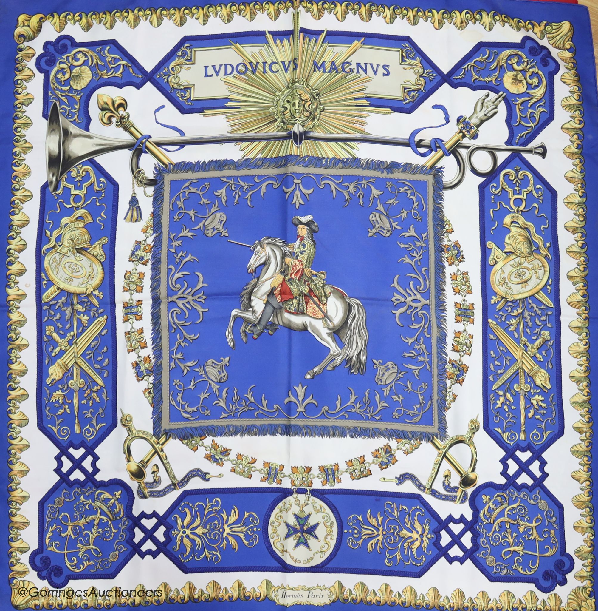 Three vintage Hermes silk scarves, 'Caparacons' (white ground), 'La Camargue' (red ground), and 'Ludovicus Magnus' (blue ground)